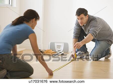 Stock Photograph - Couple measuring floor with tape measure. Fotosearch