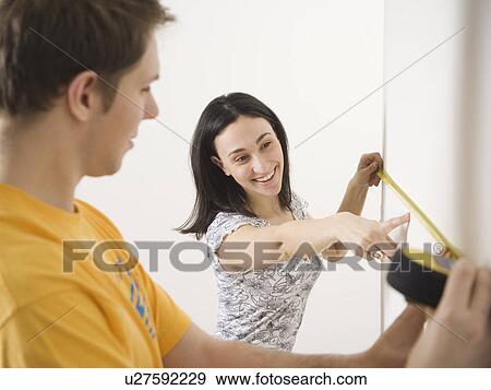Couple measuring wall View Large Photo Image Stock Photo - Couple measuring wall. Fotosearch