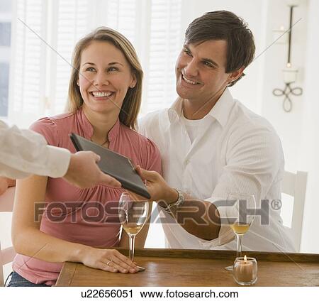 Stock Image - Couple paying at restaurant. Fotosearch