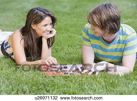 Stock Image - Couple playing checkers in grass. Fotosearch