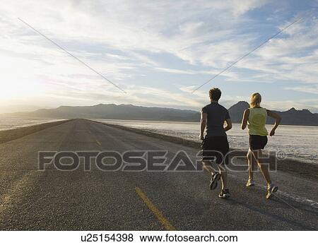 Stock Photo - Couple running on road, Utah, United States. Fotosearch