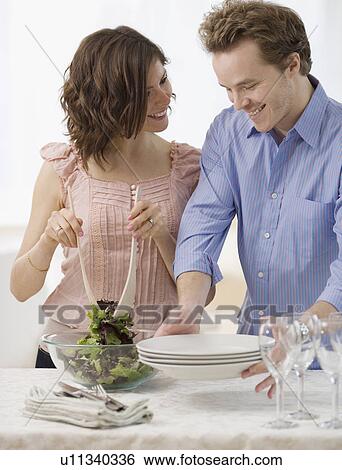 Couple setting table and tossing salad View Large Photo Image Stock Photograph - Couple setting table and tossing salad. Fotosearch