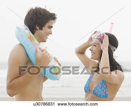 Couple smiling at each other at beach View Large Photo Image Stock Image - Couple smiling at each other at beach. Fotosearch