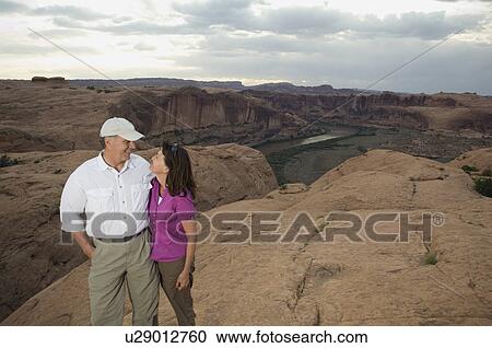 Stock Image - Couple smiling at each other on rock formation. Fotosearch