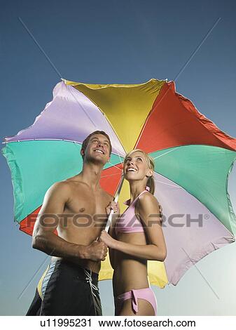 Couple standing under beach umbrella View Large Photo Image Stock Image - Couple standing under beach umbrella. Fotosearch