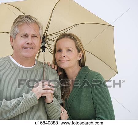 Stock Photo - Couple standing under umbrella. Fotosearch