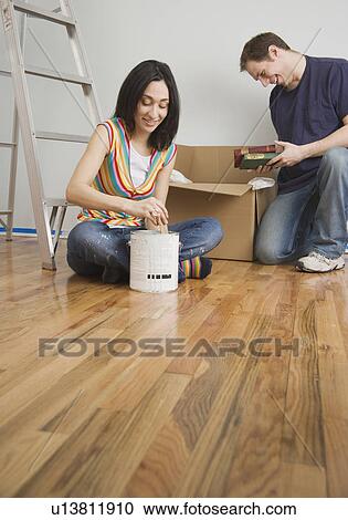 Stock Image - Couple unpacking box in new house. Fotosearch