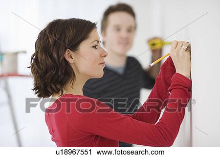 Couple using measuring tape on wall View Large Photo Image Stock Image - Couple using measuring tape on wall. Fotosearch