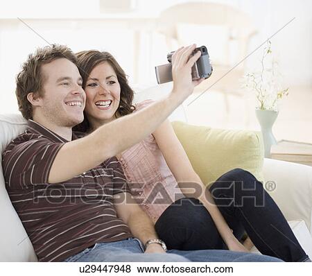 Couple video recording selves on sofa View Large Photo Image Stock Photo - Couple video recording selves on sofa. Fotosearch