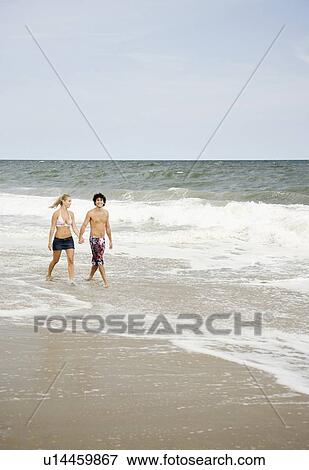 Couple walking in ocean surf View Large Photo Image Stock Photo - Couple walking in ocean surf. Fotosearch