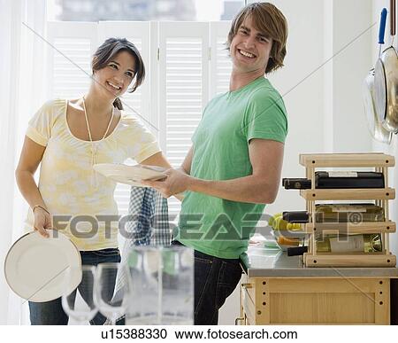Stock Image - Couple washing dishes in kitchen. Fotosearch