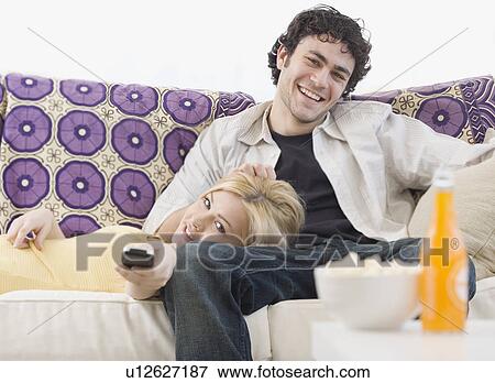 Stock Photo - Couple watching television on sofa. Fotosearch