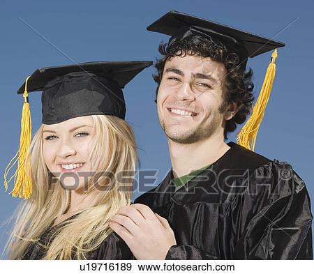 Stock Photo - Couple wearing graduation caps and gowns. Fotosearch