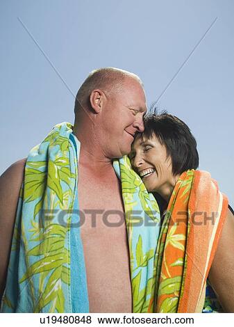 Couple with beach towels hugging View Large Photo Image Stock Photo - Couple with beach towels hugging. Fotosearch