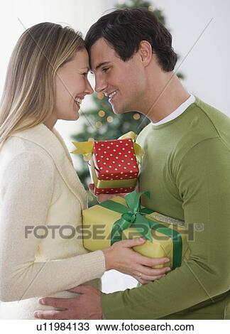 Stock Image - Couple with gifts hugging. Fotosearch