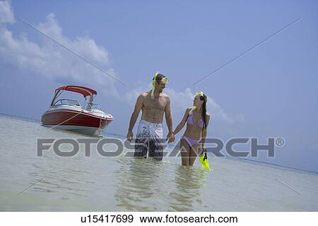 Stock Photo - Couple with snorkeling gear walking in water, Florida, United States. Fotosearch