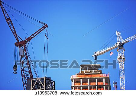 Stock Photo - Cranes and high-rise under blue sky. Fotosearch