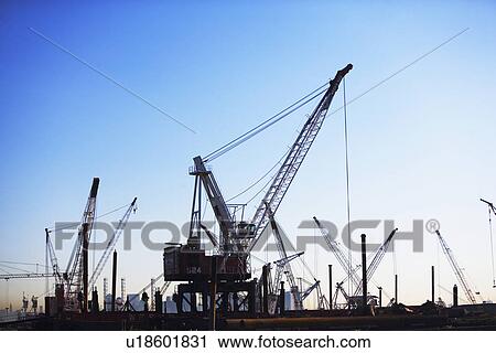Stock Image - Cranes on dock at sunset. Fotosearch