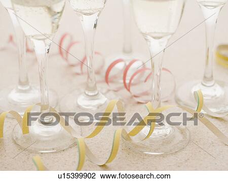Stock Image - Curls of confetti with wineglasses. Fotosearch