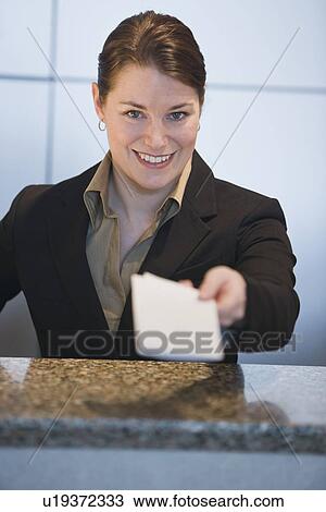 Stock Image - Customer service representative handing ticket over counter. Fotosearch