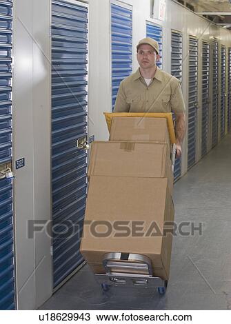 Delivery man pushing stack of packages View Large Photo Image Stock Image - Delivery man pushing stack of packages. Fotosearch