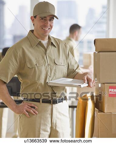 Delivery man standing next to packages View Large Photo Image Stock Photo - Delivery man standing next to packages. Fotosearch