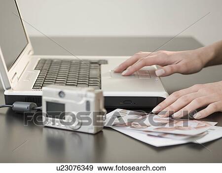 Stock Photo - Digital camera and photographs next to laptop. Fotosearch