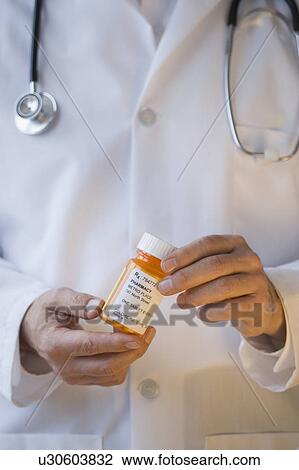 Stock Image - Doctor holding prescription bottle. Fotosearch