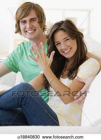 Stock Image - Engaged couple showing off engagement ring. Fotosearch