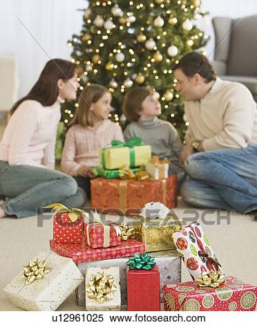 Stock Photography - Family with gifts in front of Christmas tree. Fotosearch