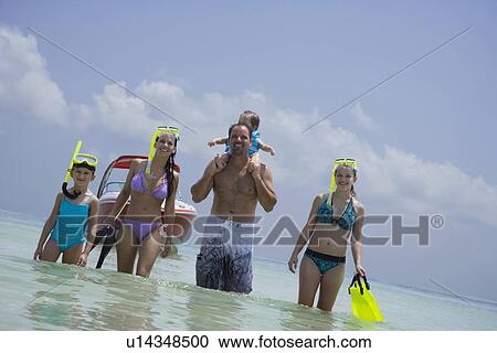 Stock Image - Family with snorkeling gear walking in water, Florida, United States. Fotosearch