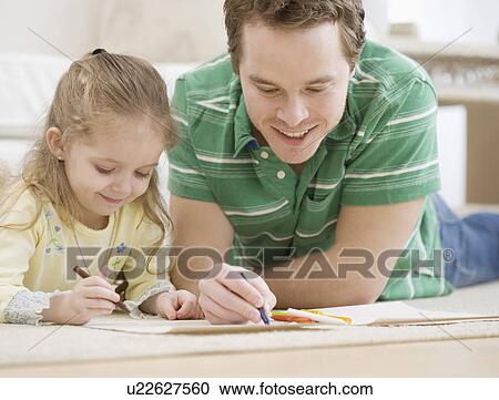 Stock Image - Father and daughter coloring on floor. Fotosearch
