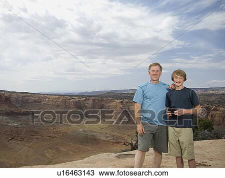 Stock Image - Father and son in front of canyon. Fotosearch