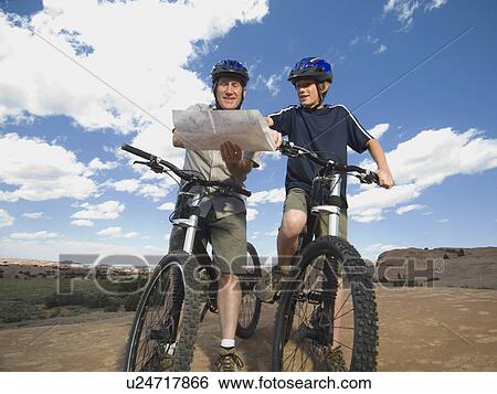 Father and son on mountain bikes with map View Large Photo Image Stock Photograph - Father and son on mountain bikes with map. Fotosearch