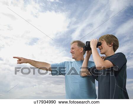 Stock Image - Father and son using binoculars. Fotosearch