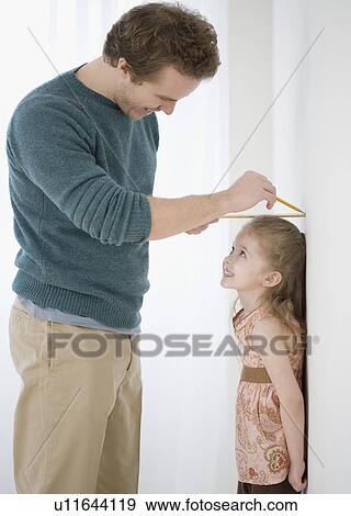 Father measuring daughter’s height on wall View Large Photo Image Stock Photo - Father measuring daughter’s height on wall. Fotosearch