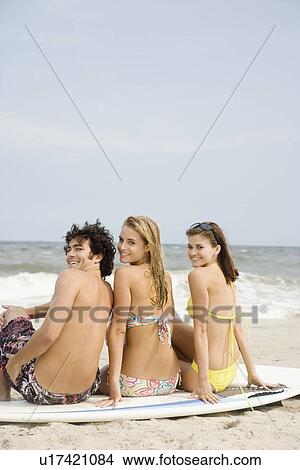 Friends sitting on surfboard at beach View Large Photo Image Picture - Friends sitting on surfboard at beach. Fotosearch
