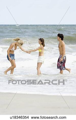 Friends standing in ocean surf View Large Photo Image Picture - Friends standing in ocean surf. Fotosearch