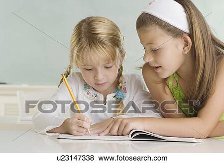 Girl helping classmate at desk View Large Photo Image Stock Photo - Girl helping classmate at desk. Fotosearch