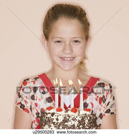 Stock Image - Girl holding birthday cake with lit candles. Fotosearch