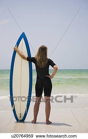 Stock Photo - Girl holding surfboard in sand, Florida, United States. Fotosearch