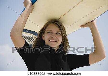 Stock Image - Girl holding surfboard on head, Florida, United States. Fotosearch