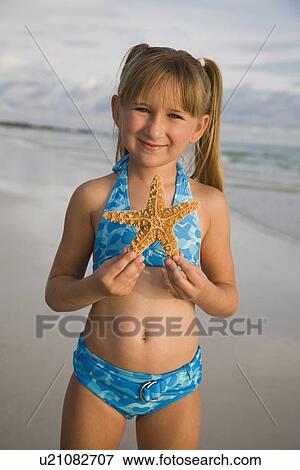 Stock Photo - Girl holding up starfish, Florida, United States. Fotosearch