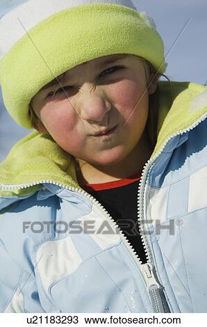 Stock Image - Girl in jacket and hat making a face. Fotosearch
