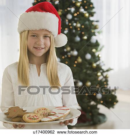 Girl in Santa Claus hat holding plate of cookies View Large Photo Image Stock Image - Girl in Santa Claus hat holding plate of cookies. Fotosearch