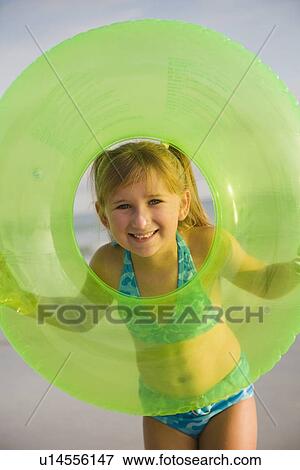 Stock Photo - Girl looking through middle of inner tube, Florida, United States. Fotosearch