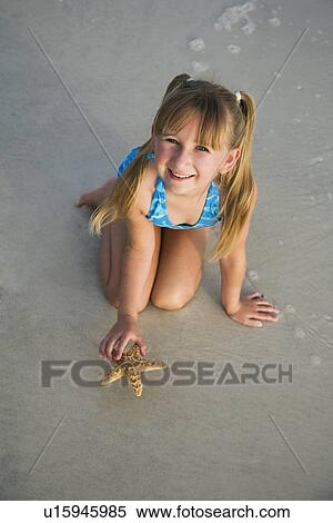 Girl picking up starfish, Florida, United States View Large Photo Image Stock Photography - Girl picking up starfish, Florida, United States. Fotosearch