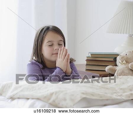 Girl praying next to bed View Large Photo Image Stock Photo - Girl praying next to bed. Fotosearch