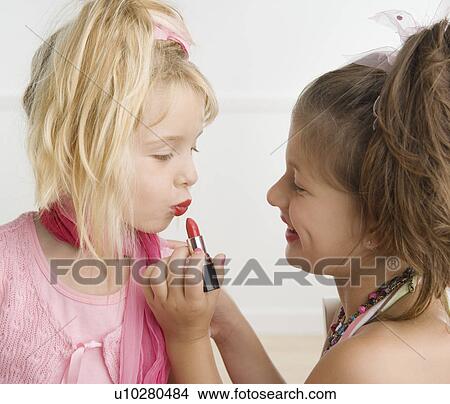 Girl putting lipstick on sister View Large Photo Image Picture - Girl putting lipstick on sister. Fotosearch