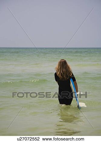 Girl walking into water with surfboard, Florida, United States View Large Photo Image Stock Image - Girl walking into water with surfboard, Florida, United States. Fotosearch